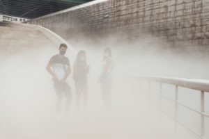 Three people with masks on a pollution cloud